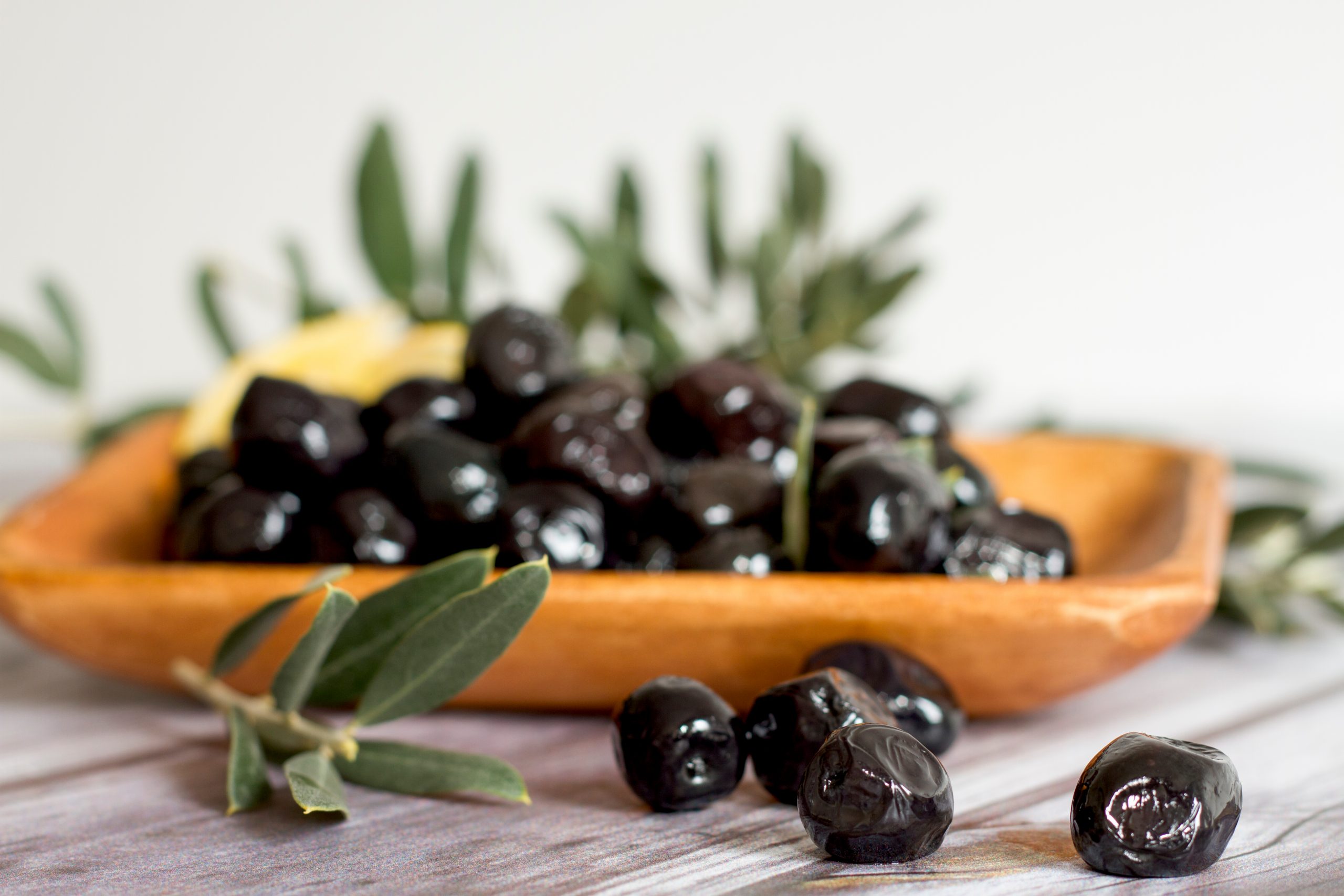 Black,Olives,With,Leaves,And,Lemon.,Black,Olives,At,Wooden